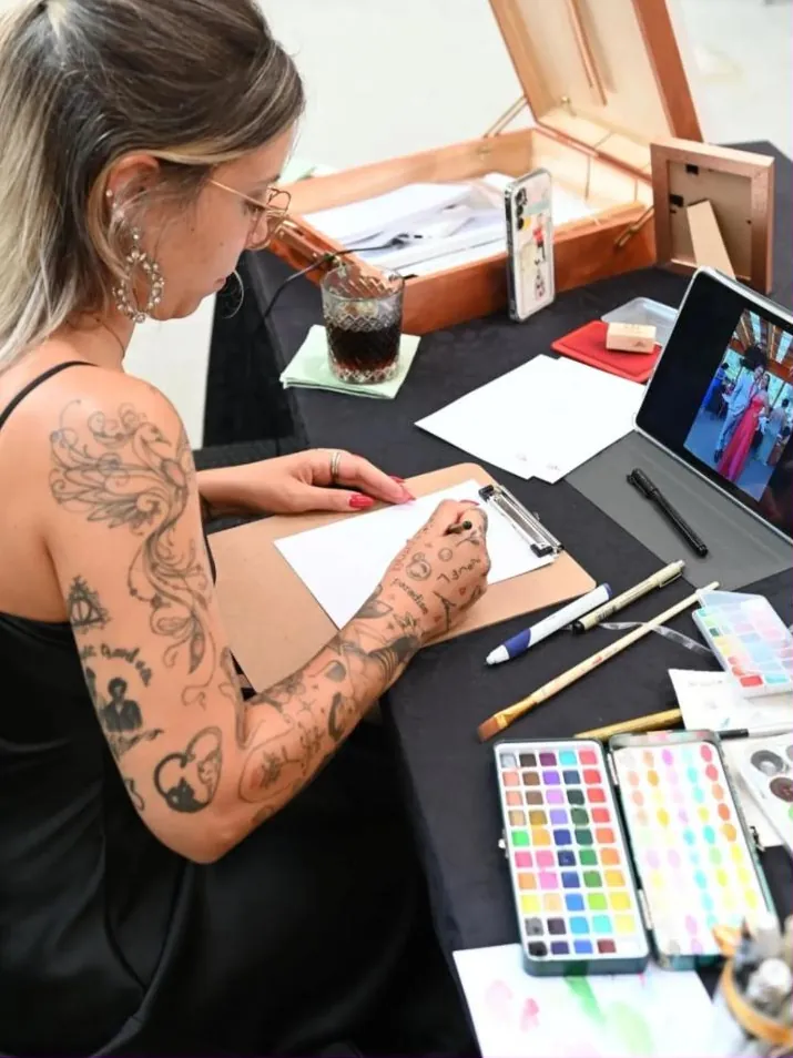 A Maria a desenhar com a fotografia do convidado no tablet à frente