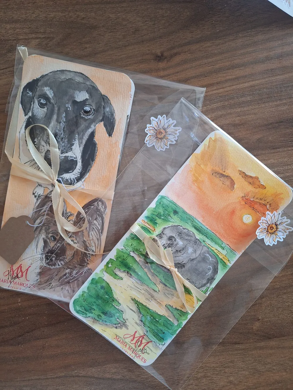 Dois marcadores de livros com retratos de cães, embrulhados com fita