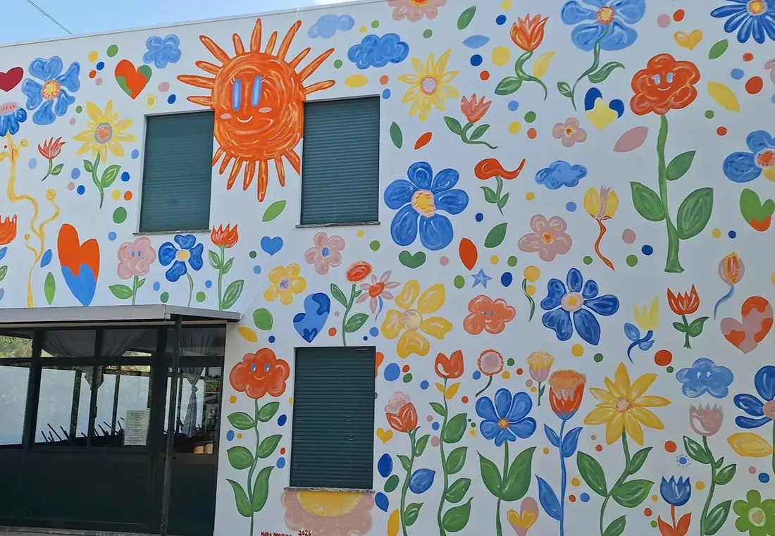 Fachada da escola pintada com flores, corações e um sol sorridente
