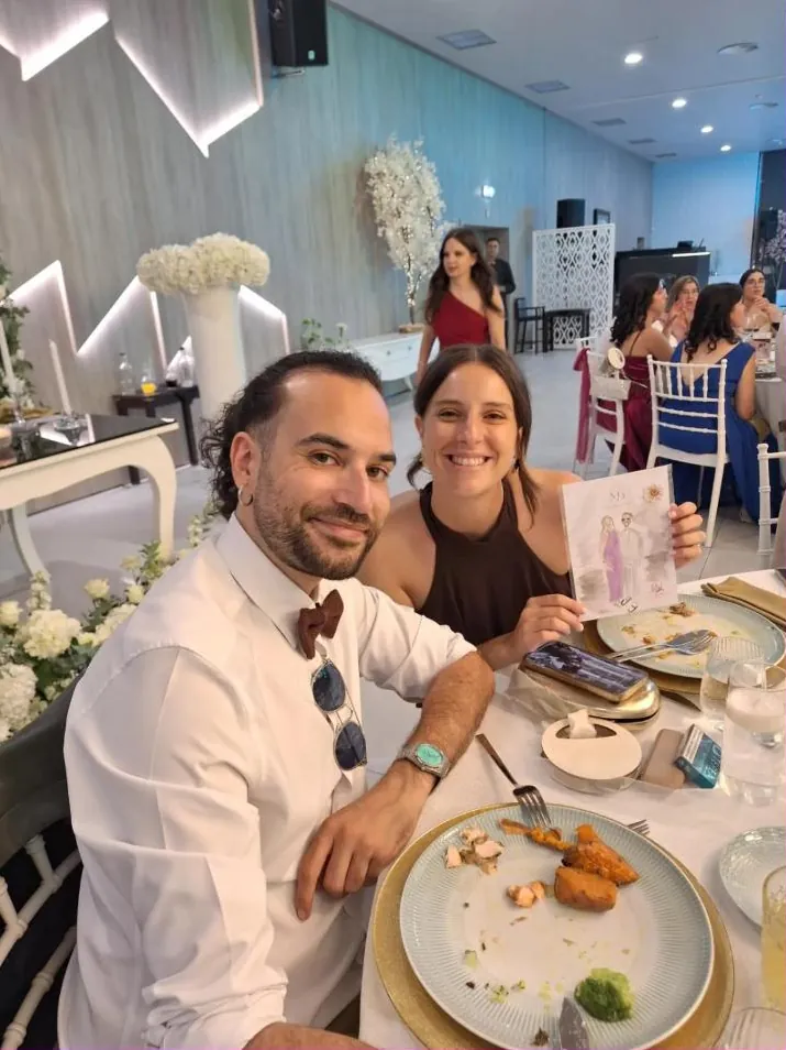 Dois convidados sorridentes com a ilustração na mão