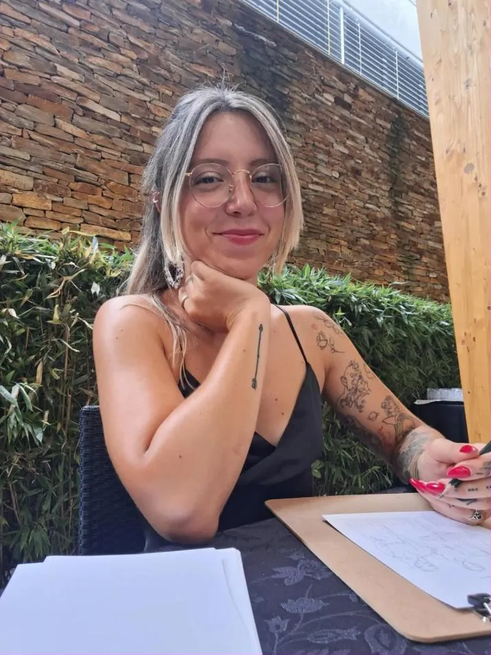 Retrato da Maria Marques, de óculos, a sorrir com a mão no queixo