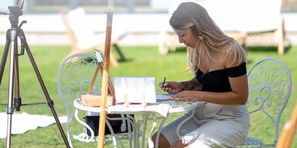 Maria a desenhar numa mesa de jardim, ao ar livre